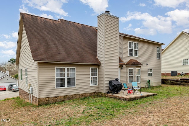 back of house featuring a patio, a lawn, and a chimney