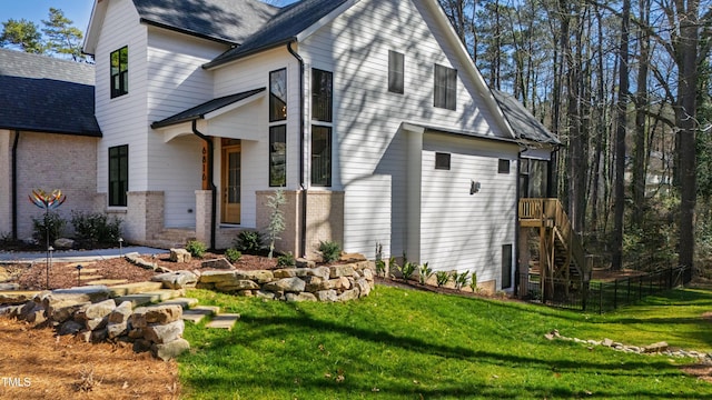 view of home's exterior featuring brick siding, a lawn, and stairs