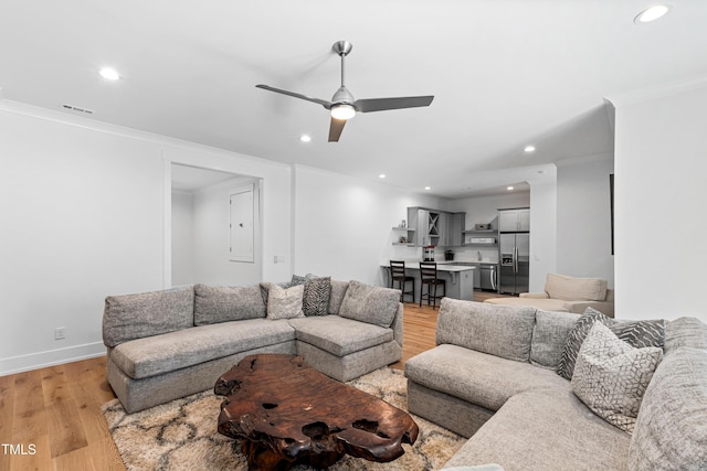 living area with visible vents, crown molding, baseboards, light wood-type flooring, and recessed lighting