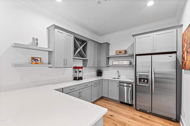 kitchen featuring open shelves, stainless steel appliances, gray cabinets, and a sink