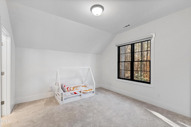 unfurnished bedroom featuring visible vents, carpet floors, baseboards, and vaulted ceiling