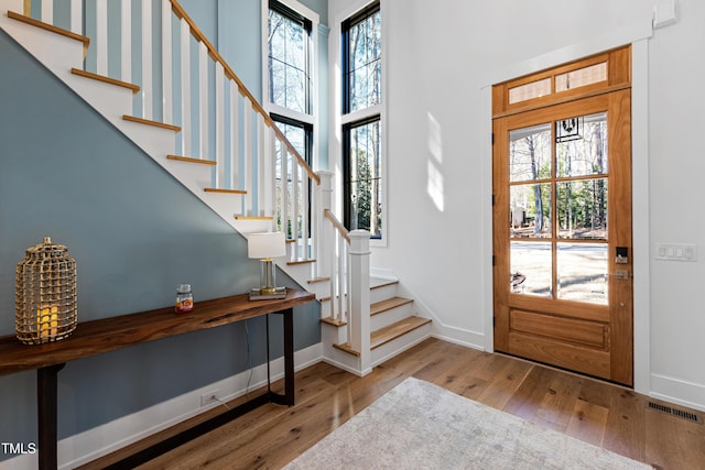 entrance foyer with stairway, a high ceiling, baseboards, and wood-type flooring