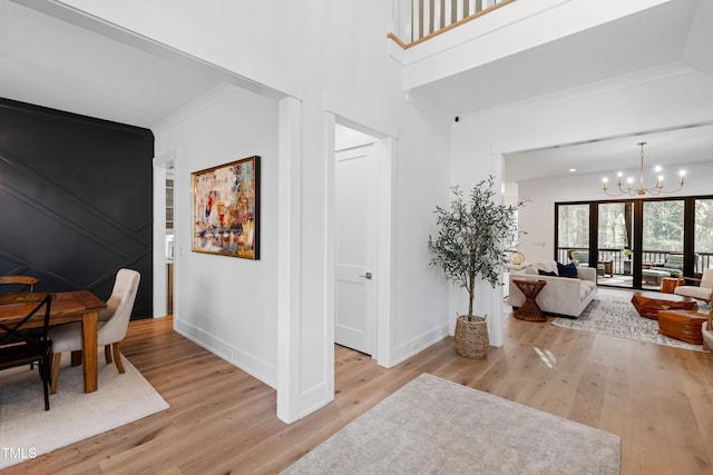 interior space featuring light wood-type flooring, baseboards, a notable chandelier, and ornamental molding