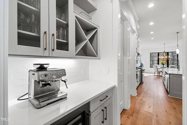 interior space featuring pendant lighting, gray cabinets, recessed lighting, light wood finished floors, and glass insert cabinets