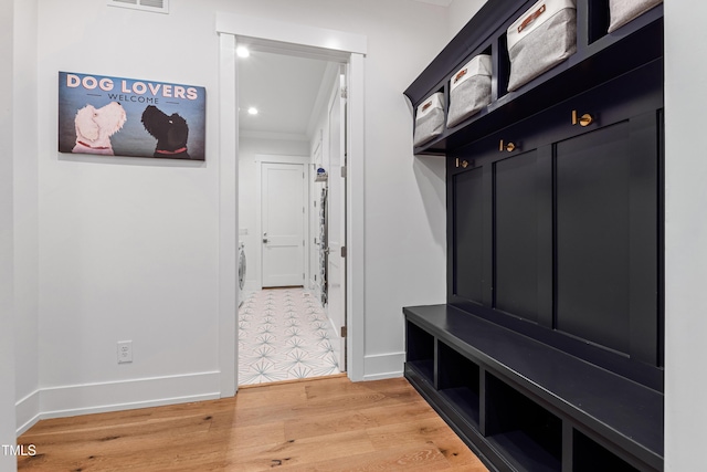 mudroom with visible vents, crown molding, light wood-type flooring, and baseboards