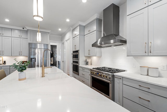 kitchen featuring stainless steel appliances, light stone countertops, wall chimney exhaust hood, and gray cabinets