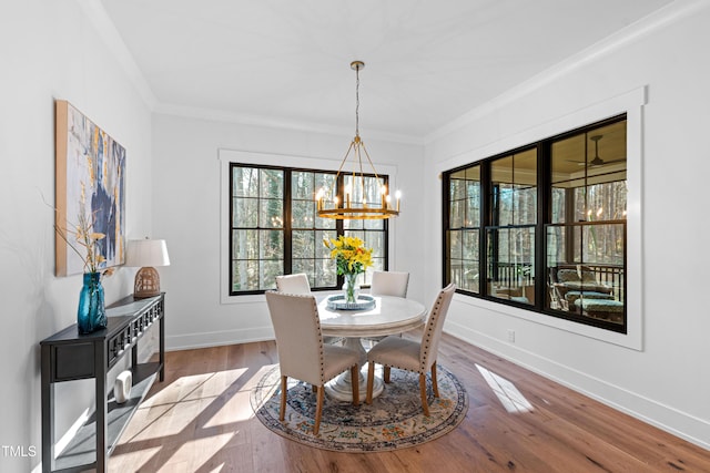 dining room with ornamental molding, an inviting chandelier, baseboards, and wood finished floors