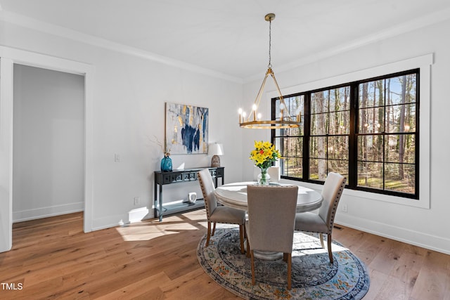 dining space with a notable chandelier, hardwood / wood-style flooring, baseboards, and ornamental molding