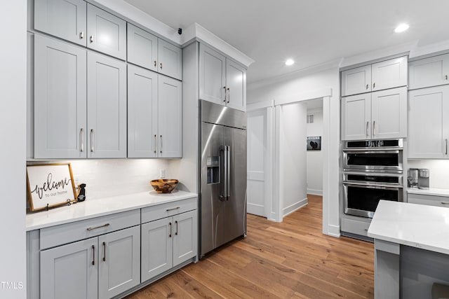 kitchen featuring light wood finished floors, recessed lighting, gray cabinetry, and stainless steel appliances