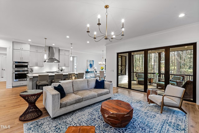 living area with recessed lighting, light wood-type flooring, a chandelier, and ornamental molding