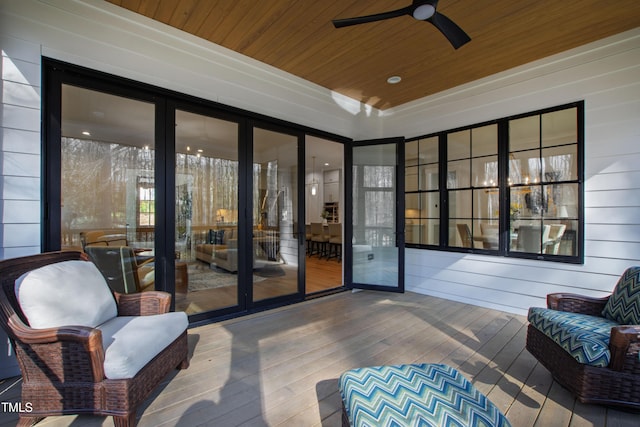 sunroom / solarium with wood ceiling, a raised ceiling, and ceiling fan