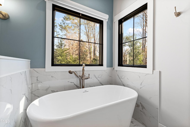 full bath with a wainscoted wall, a freestanding tub, and marble finish floor