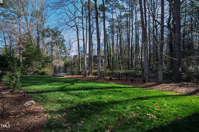 view of yard with a trampoline and fence