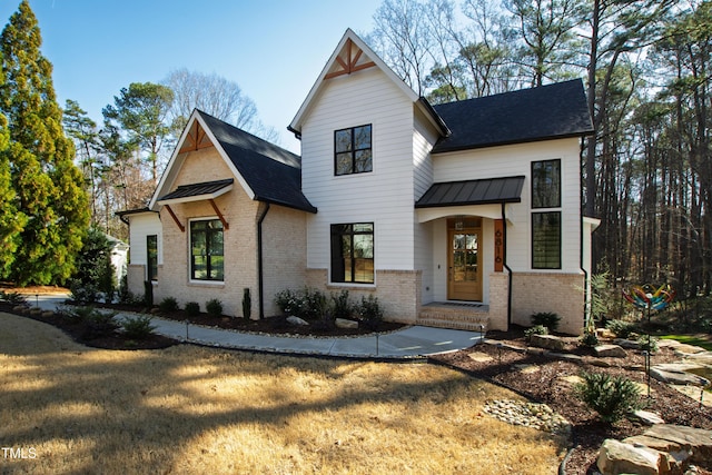 modern farmhouse with metal roof, brick siding, a shingled roof, and a standing seam roof