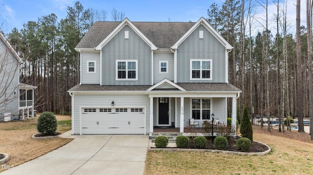 view of front of home featuring a front yard, an attached garage, covered porch, concrete driveway, and board and batten siding