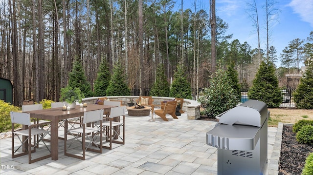 view of patio featuring area for grilling, a fire pit, outdoor dining area, and fence