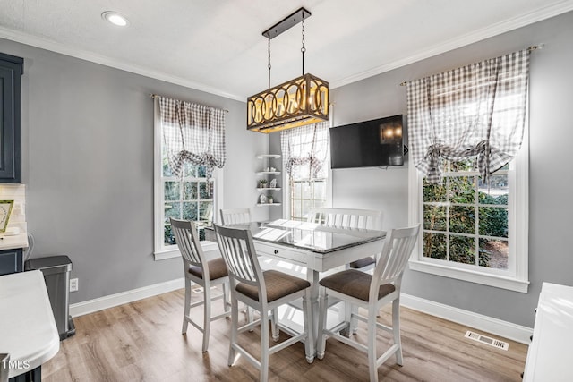 dining area with crown molding, baseboards, visible vents, and light wood finished floors