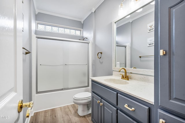 bathroom with toilet, ornamental molding, wood finished floors, enclosed tub / shower combo, and vanity