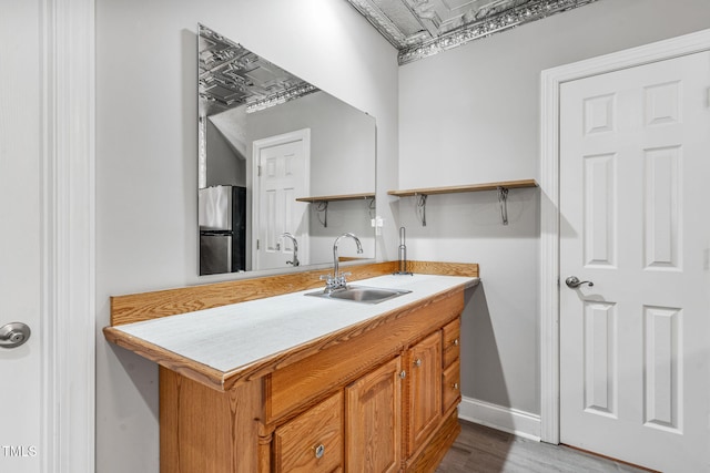 kitchen featuring open shelves, freestanding refrigerator, a sink, light countertops, and brown cabinets