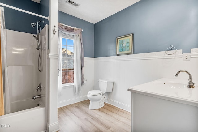 full bath featuring visible vents, toilet, wood finished floors, wainscoting, and tub / shower combination