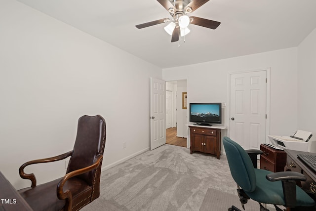 office space with a ceiling fan, light colored carpet, and baseboards