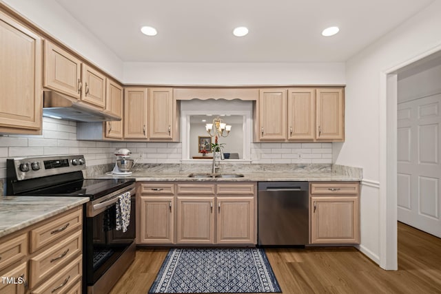 kitchen featuring wood finished floors, light brown cabinetry, a sink, under cabinet range hood, and appliances with stainless steel finishes