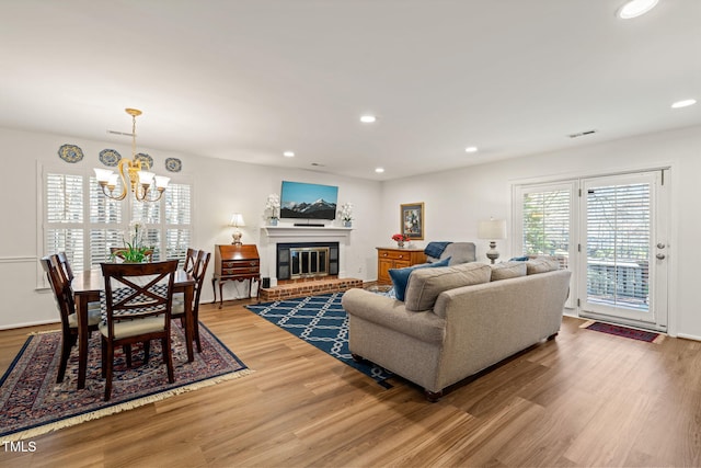 living area featuring recessed lighting, visible vents, a brick fireplace, and light wood finished floors