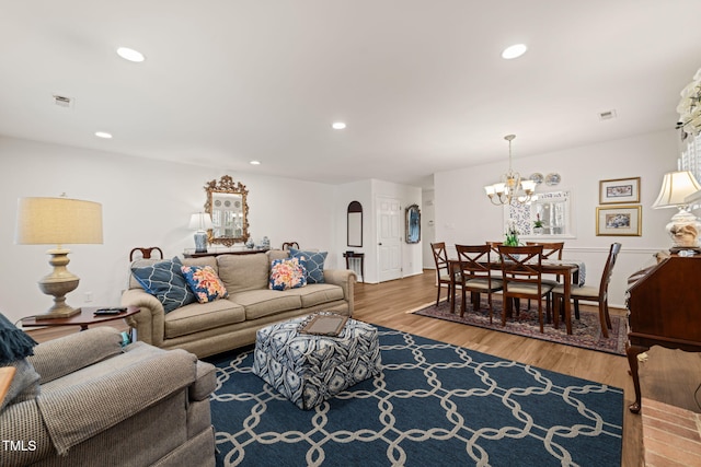 living room with recessed lighting, wood finished floors, visible vents, and arched walkways