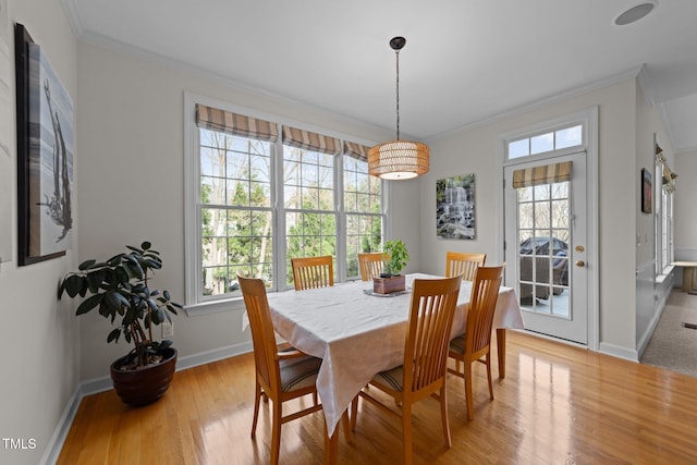 dining area featuring a wealth of natural light, baseboards, crown molding, and light wood finished floors