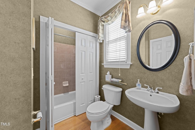 bathroom with wood finished floors, baseboards, a sink, crown molding, and toilet