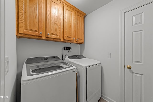 clothes washing area featuring cabinet space and separate washer and dryer