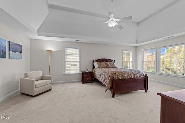 bedroom featuring a ceiling fan, baseboards, visible vents, a tray ceiling, and light carpet