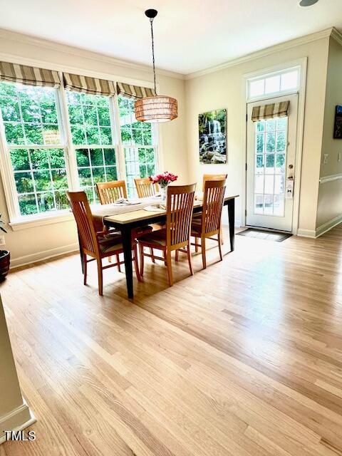 dining space featuring crown molding, light wood-style flooring, and baseboards