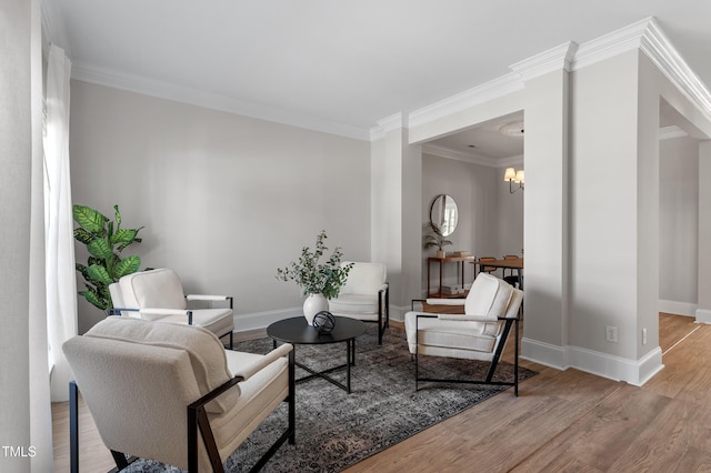 living room featuring a chandelier, ornamental molding, baseboards, and wood finished floors