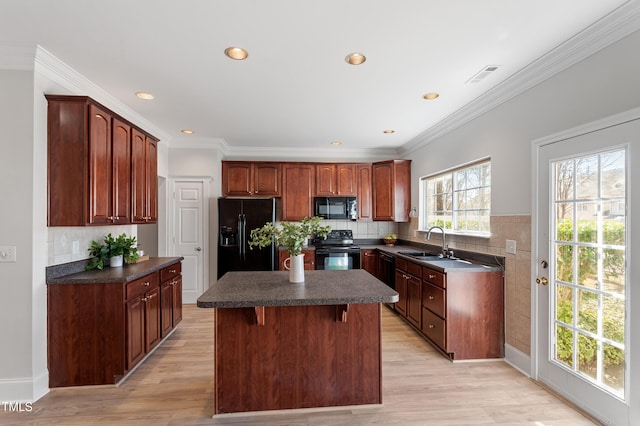 kitchen featuring visible vents, black appliances, a sink, dark countertops, and a center island