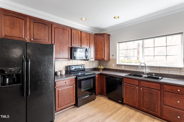 kitchen with backsplash, a sink, black appliances, dark countertops, and a wealth of natural light