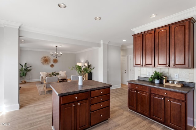 kitchen with light wood-style floors, tasteful backsplash, dark countertops, and ornamental molding