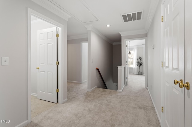 hall with visible vents, an upstairs landing, ornamental molding, carpet, and attic access