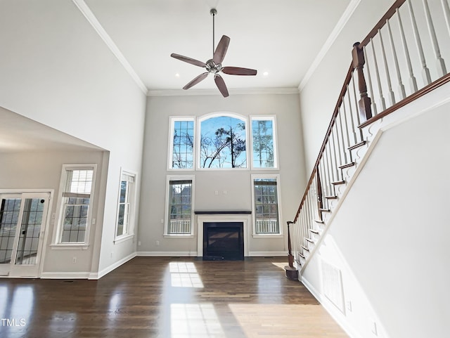 unfurnished living room with wood finished floors, a healthy amount of sunlight, and ornamental molding