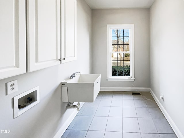 laundry room featuring visible vents, baseboards, light tile patterned flooring, cabinet space, and a sink