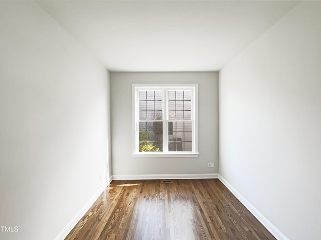 empty room with visible vents, baseboards, and dark wood-style flooring