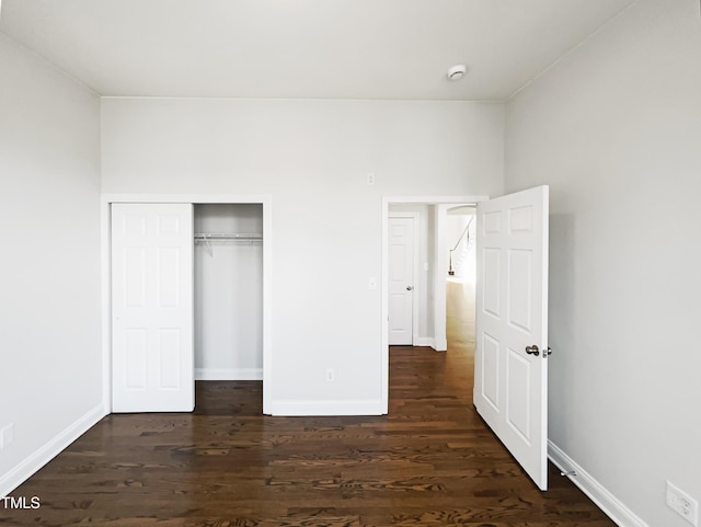 unfurnished bedroom featuring a closet, baseboards, and dark wood-style floors