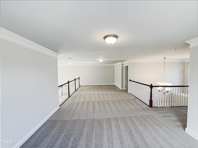 carpeted spare room with baseboards, a notable chandelier, and ornamental molding