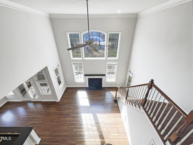 living room featuring ceiling fan, a towering ceiling, a fireplace, and crown molding