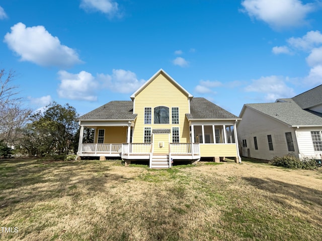 back of house with a yard, a sunroom, and roof with shingles