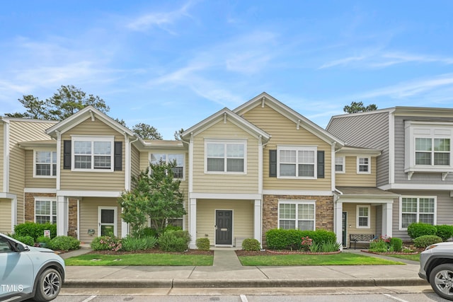 townhome / multi-family property featuring stone siding and uncovered parking