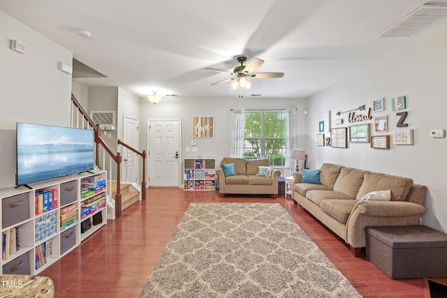 living room with stairway, wood finished floors, visible vents, and ceiling fan