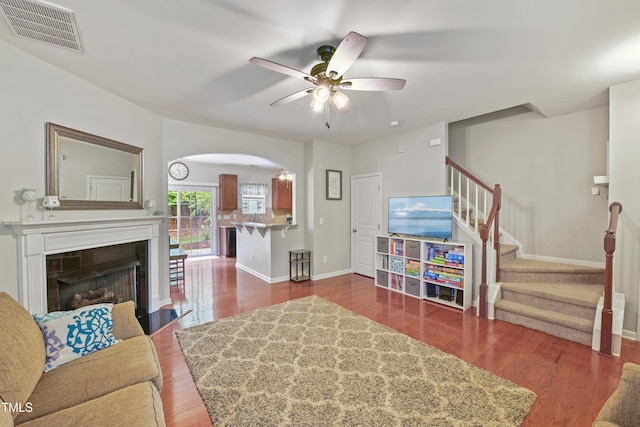 living room featuring visible vents, baseboards, stairway, a fireplace, and wood finished floors