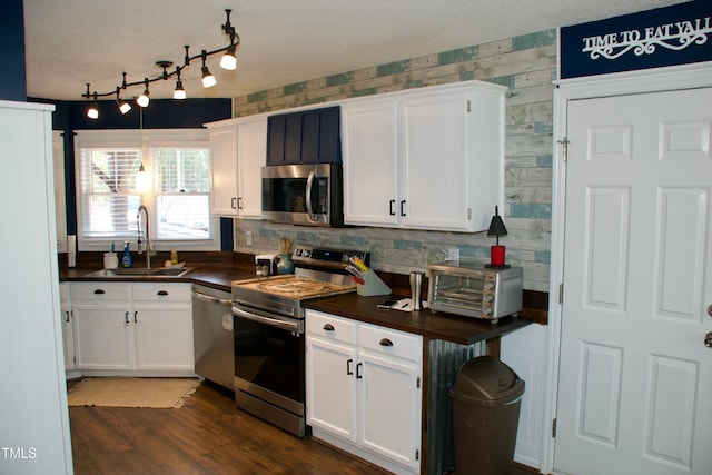 kitchen with a toaster, dark wood-style flooring, a sink, stainless steel appliances, and white cabinetry