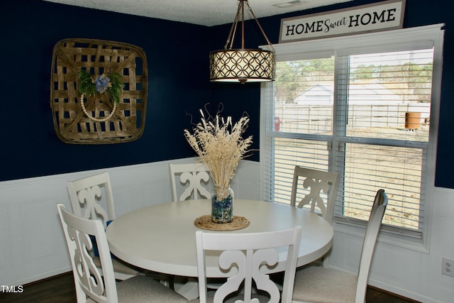 dining area with visible vents, dark wood-type flooring, and wainscoting